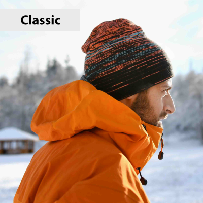 Person wearing an orange jacket and striped beanie in a snowy landscape