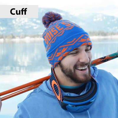 Man wearing a blue and orange knit hat with 'Boise' text, standing by a body of water.