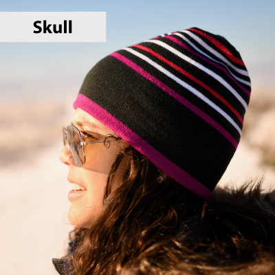 Person wearing a black beanie with pink and white stripes against a blurred natural background