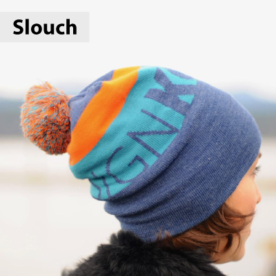 Colorful slouchy beanie with pom-pom on a blurred background